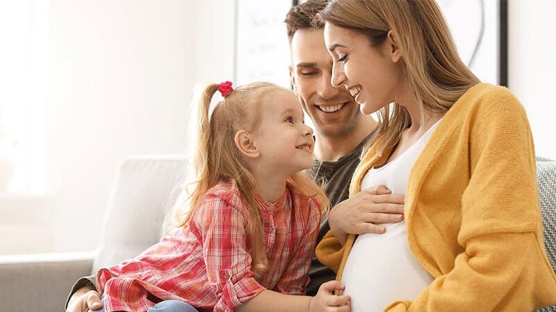 Growing family relaxing on a sofa, anticipating the arrival of their new baby